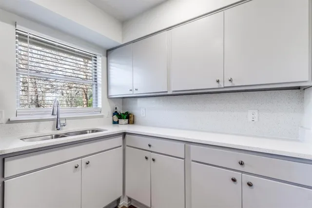 a kitchen with white cabinets and a window