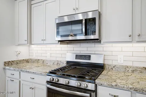 a kitchen with granite countertop a stove and a microwave