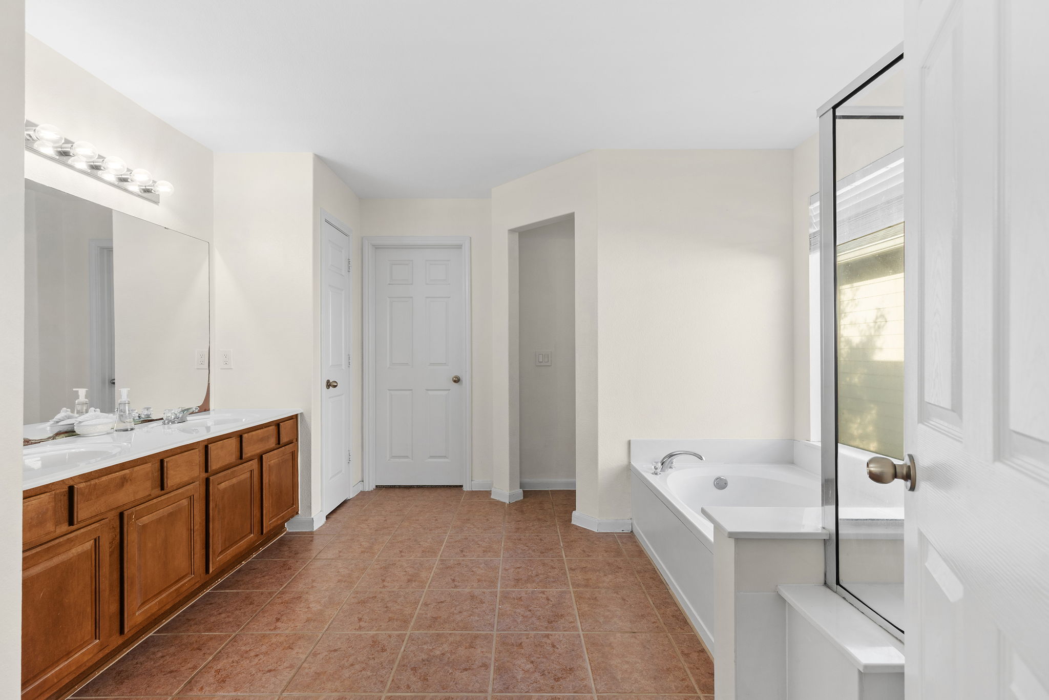 3517 Shiraz Loop Round Rock, TX 78665 - Photo 18 of 40 Bathroom featuring a dual vanity with wood cabinetry and a light-toned countertop, a built-in soaking tub, and ceramic tile flooring