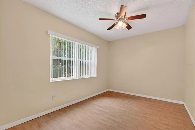 an empty room with ceiling fan and window