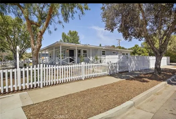 a view of a house with a small yard and wooden fence