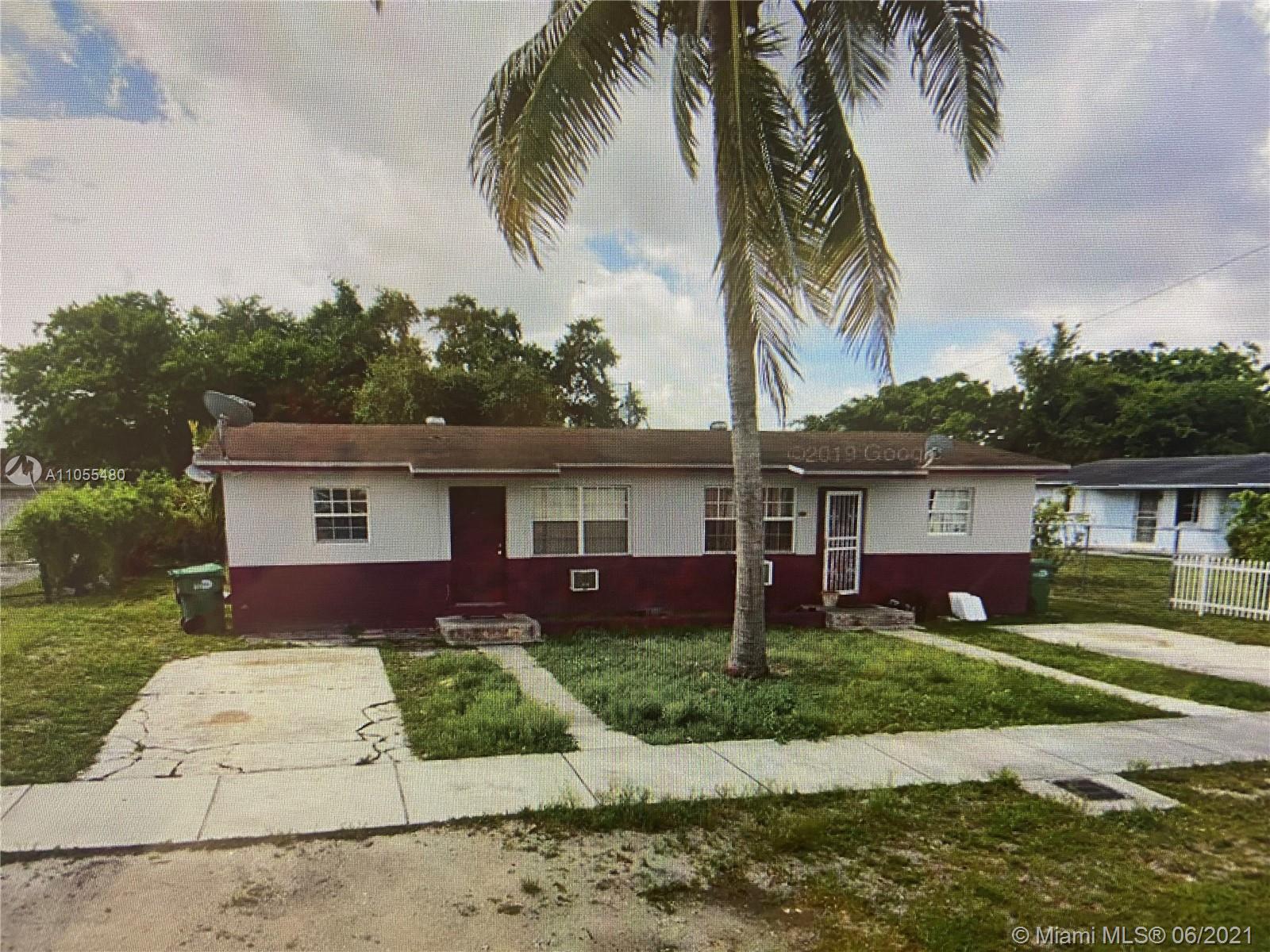 front view of house with a yard and palm trees
