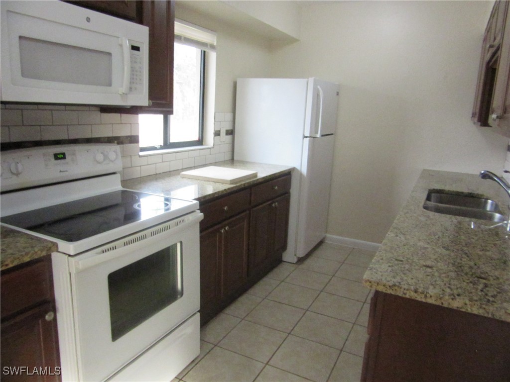 3215 Skyline Boulevard, Unit C Cape Coral, FL 33914 - Photo 19 of 25 a kitchen with granite countertop a sink stove and cabinets