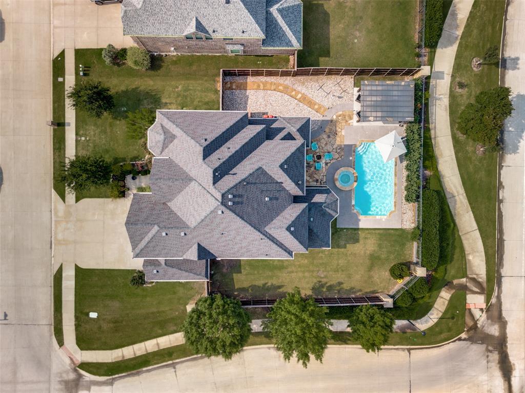 1461 Ramsbury Lane Prosper, TX 75078 - Photo 30 of 30 Expansive corner lot featuring a multi-gabled roofline, a rectangular swimming pool with an integrated circular spa, and a patterned hardscape patio
