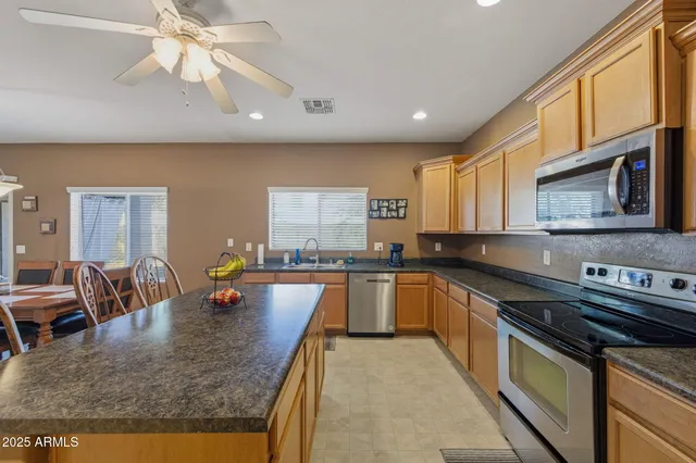 a kitchen with stainless steel appliances granite countertop a sink a stove counter space and living room view
