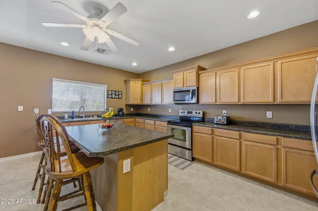 a kitchen with stainless steel appliances granite countertop a table chairs sink and cabinets