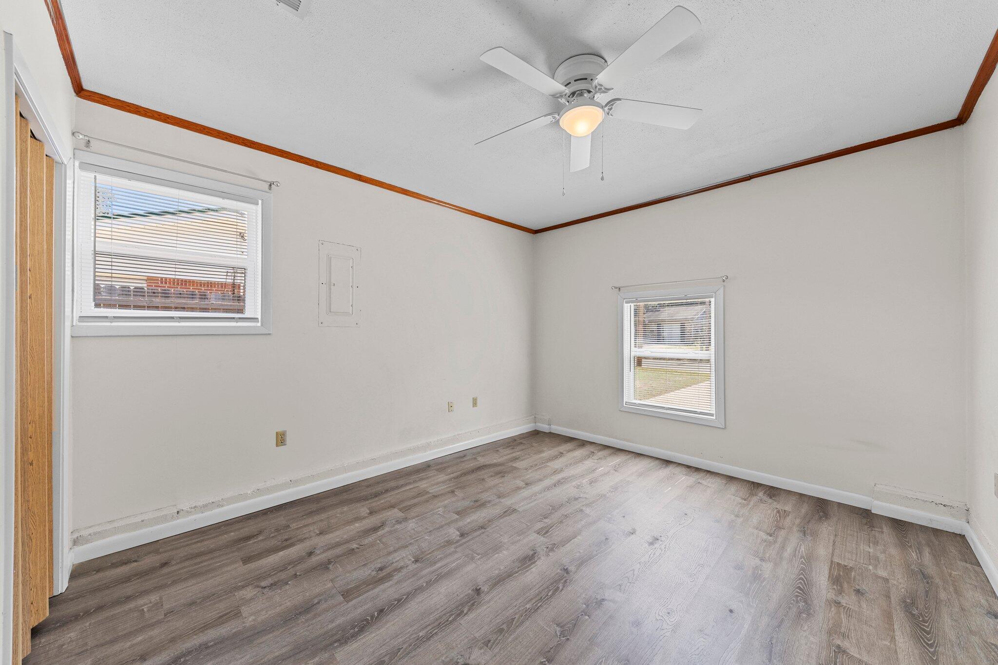 309 23rd Street Niceville, FL 32578 - Photo 19 of 33 an empty room with wooden floor chandelier fan and windows