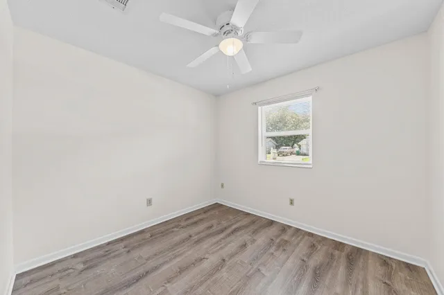 an empty room with a window and a fan