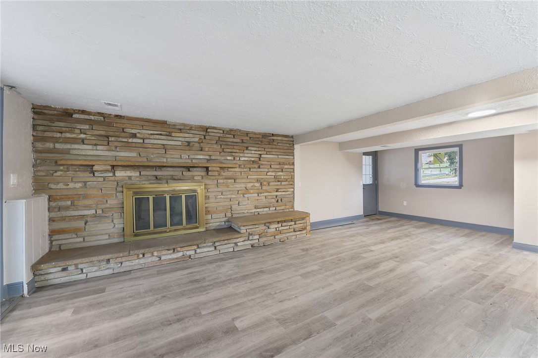 2971 Mogadore Road Akron, OH 44312 - Photo 17 of 45 Unfurnished living room featuring a textured ceiling, a fireplace, and light hardwood / wood-style floors