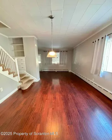 a view of empty room with wooden floor and window