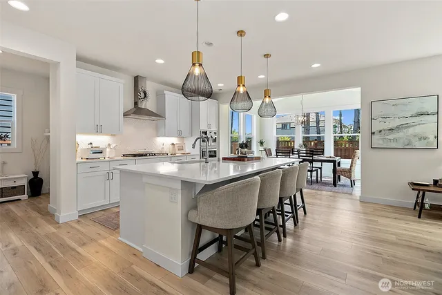 a kitchen with stainless steel appliances a dining table chairs sink and cabinets