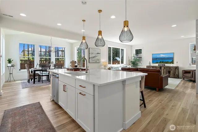 a kitchen with stainless steel appliances granite countertop a sink dishwasher a dining table and chairs with wooden floor