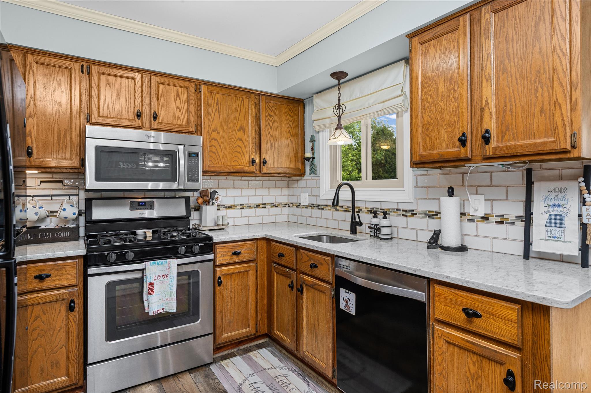 3553 Loon Lake Road Wixom, MI 48393 - Photo 7 of 25 Kitchen featuring wood cabinetry, stainless steel appliances, a subway tile backsplash with decorative accents, and light-colored countertops