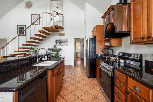 a kitchen with stainless steel appliances granite countertop a sink a stove and a refrigerator