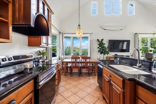 a kitchen with granite countertop a stove a sink a dining table and chairs