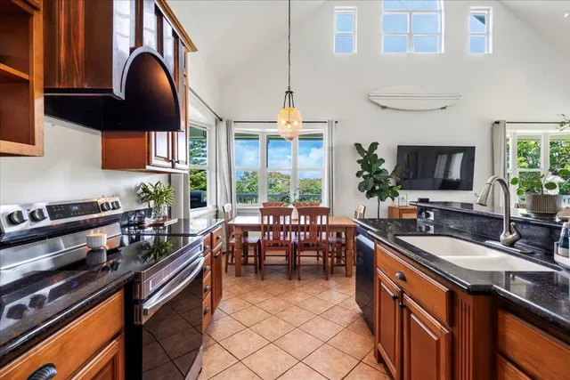 a kitchen with granite countertop a stove a sink a dining table and chairs