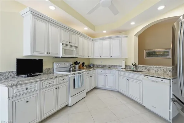 a kitchen with granite countertop white cabinets sink and stainless steel appliances
