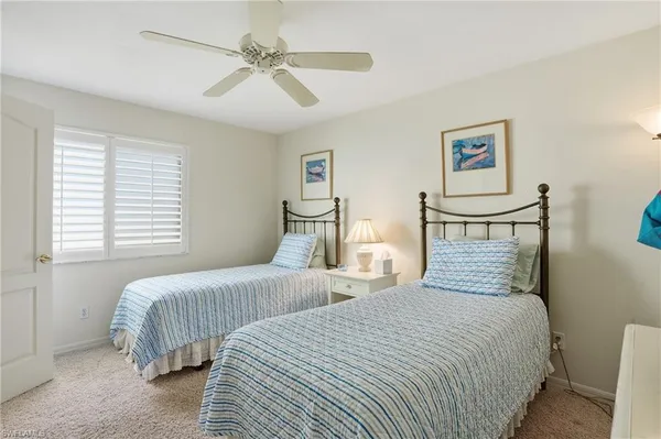 a bedroom with two beds and ceiling fan