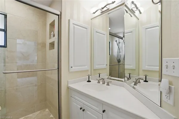 a bathroom with a double vanity sink mirror and shower