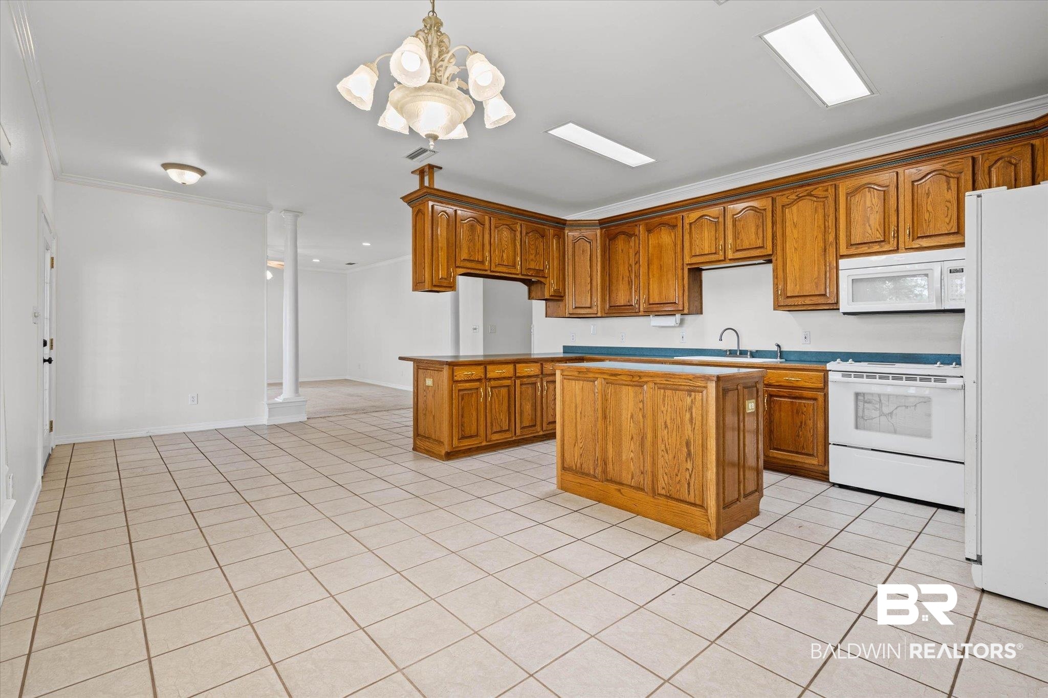 41923 Bayou Road Bay Minette, AL 36507 - Photo 11 of 35 Spacious kitchen featuring extensive wood cabinetry, two central islands, and white appliances, all set on light-toned tile flooring