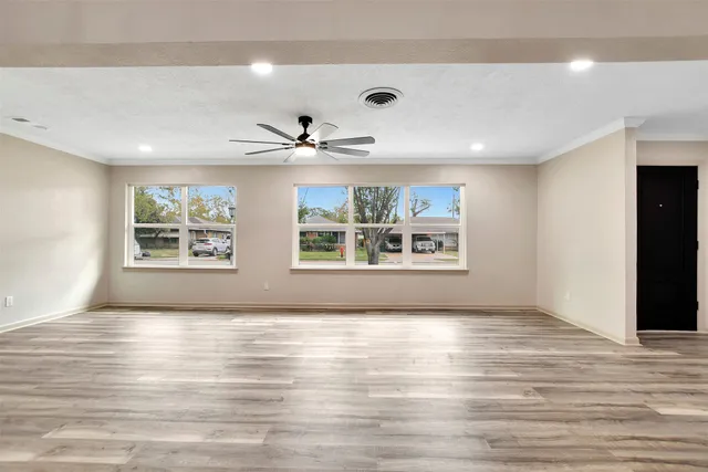 a view of an empty room with a window and wooden floor
