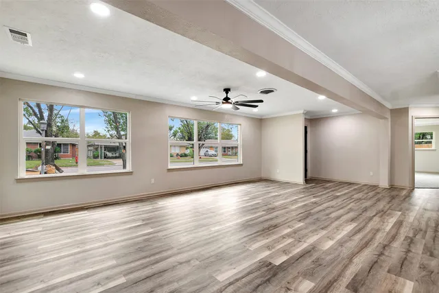 a view of an empty room with a window and wooden floor