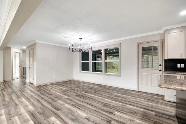 a view of an empty room with a window and kitchen view