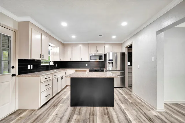 a kitchen with stainless steel appliances granite countertop a refrigerator a sink dishwasher a stove and white countertops with wooden floor