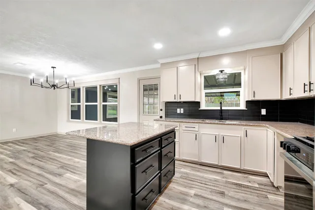 a kitchen with stainless steel appliances granite countertop a stove a sink dishwasher and a microwave oven with white cabinets