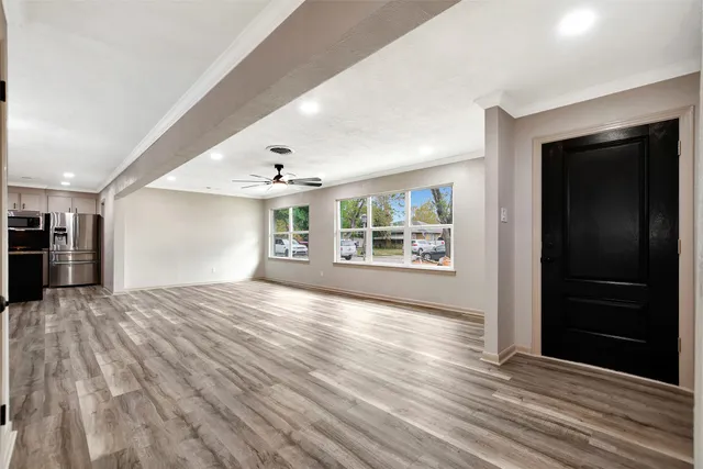 a view of an empty room with window and wooden floor