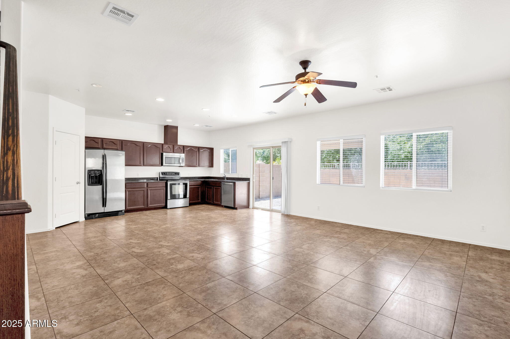 13414 North 87th Lane Peoria, AZ 85381 - Photo 6 of 45 a view of a kitchen with a stove cabinets a ceiling fan and wooden floor