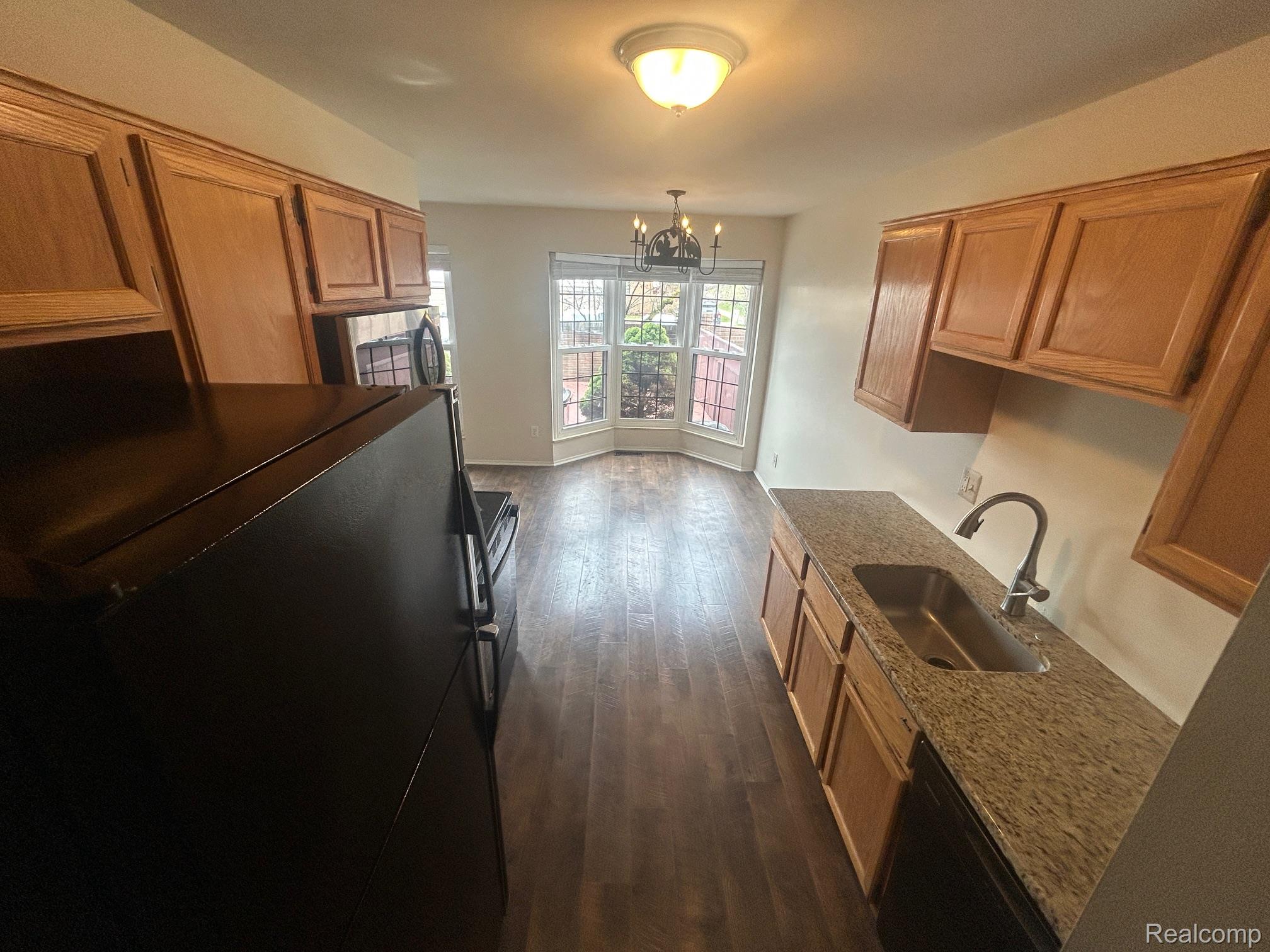 31164 Country Way Farmington, MI 48331 - Photo 12 of 33 Kitchen with black appliances, hanging lights, dark wood-style flooring, light stone countertops, and wood finish cabinets