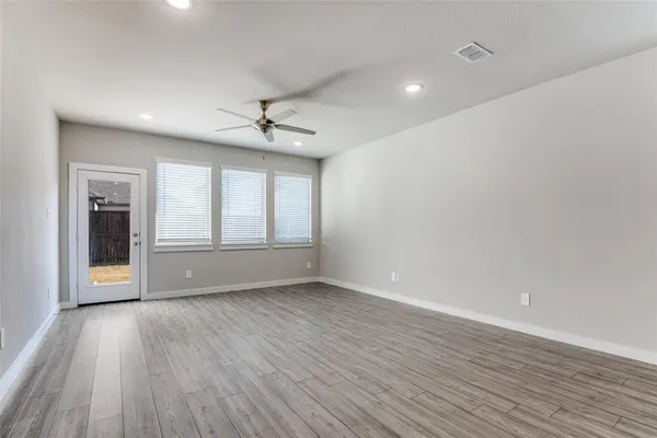 a view of an empty room with a window and wooden floor