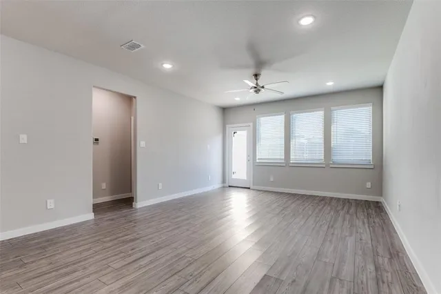 a view of an empty room with wooden floor and a window