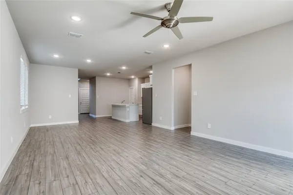 a view of a big room with wooden floor and windows