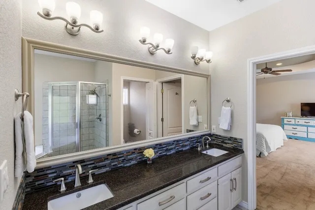 a bathroom with a granite countertop sink a toilet a mirror and shower
