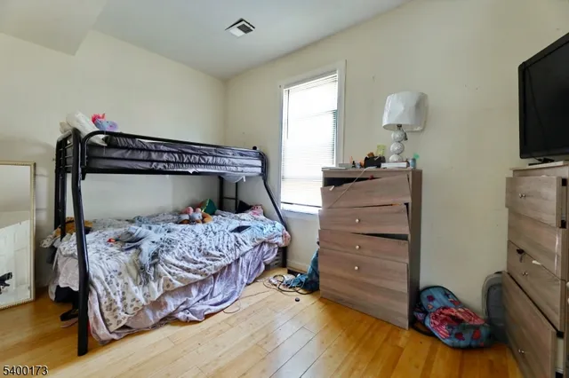 a bedroom with a bed and a flat tv screen on dresser