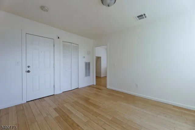 a view of an empty room with wooden floor and closet