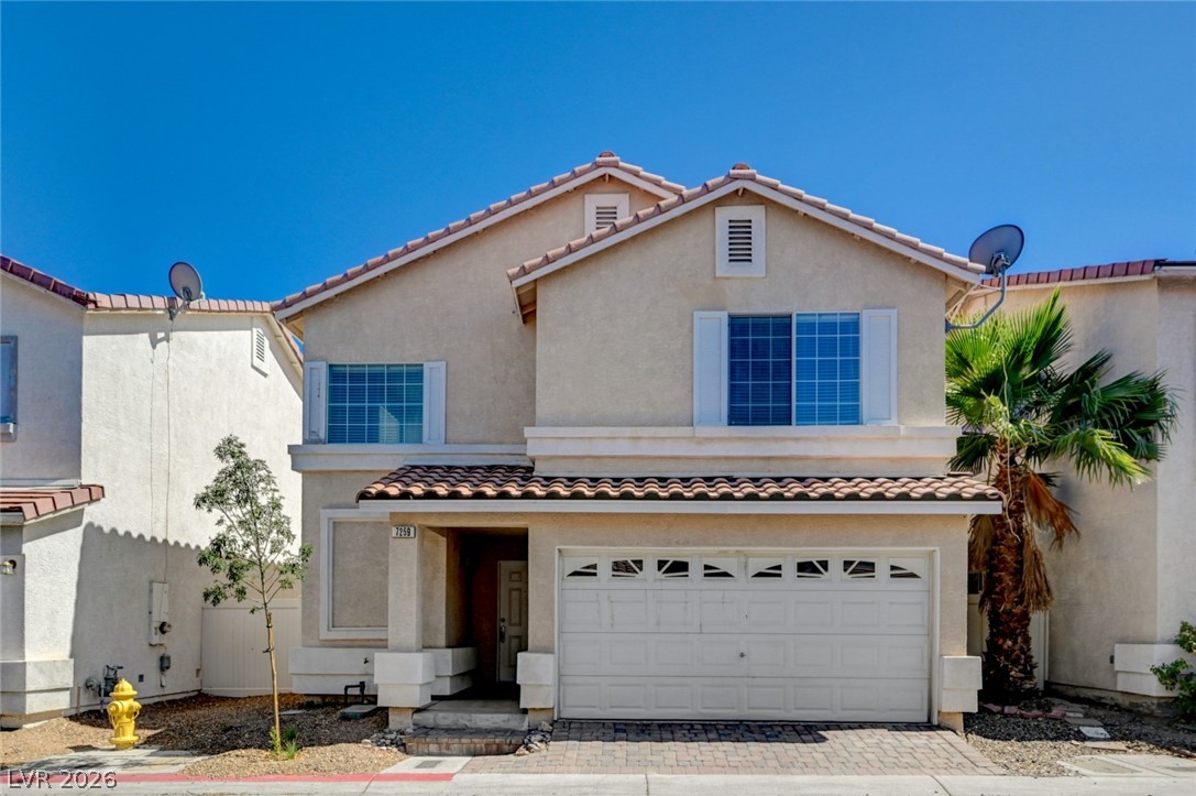 A two-story stucco home with a tile roof and attached garage offers welcoming curb appeal.