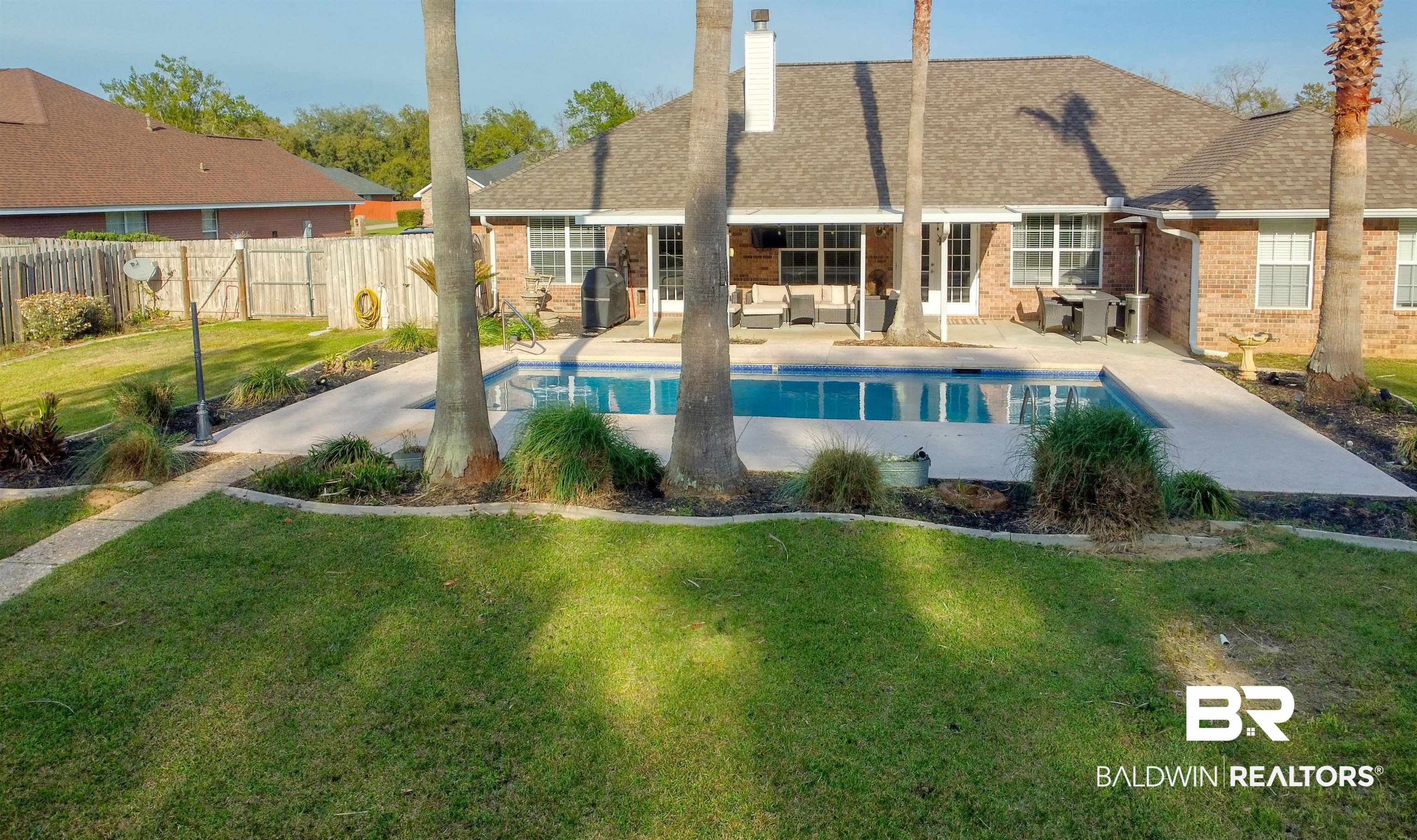 12893 Hunters Chase Foley, AL 36535 - Photo 13 of 42 Back of property featuring a patio, a fenced backyard, a fenced in pool, brick siding, and a yard