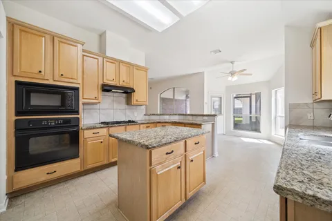 a kitchen with granite countertop a sink stove and cabinets