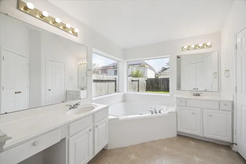 a bathroom with a tub a double vanity sink and mirror