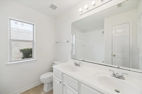 a bathroom with a granite countertop sink toilet and mirror