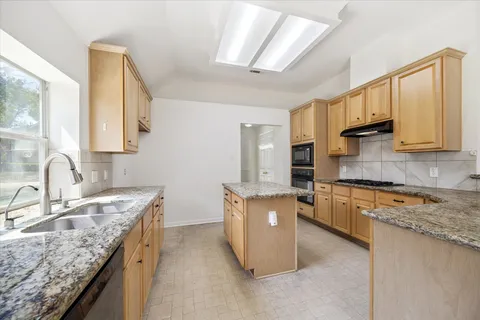 a kitchen with granite countertop a sink stove and cabinets