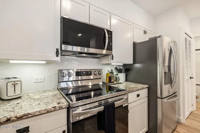 a kitchen with stainless steel appliances granite countertop a sink refrigerator and microwave