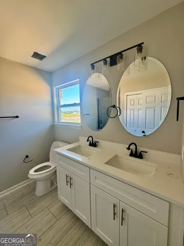 a bathroom with a double vanity sink mirror and toilet