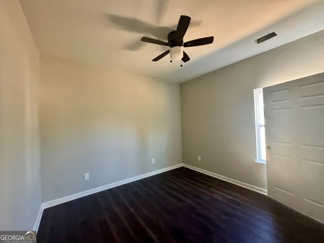 a view of empty room with wooden floor and ceiling fan