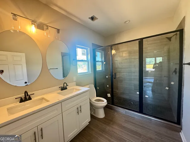 a bathroom with a double vanity sink toilet mirror and shower
