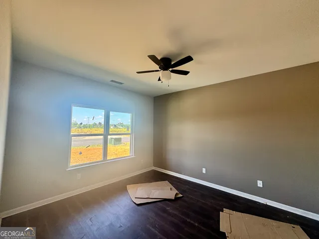 an empty room with wooden floor and ceiling fan