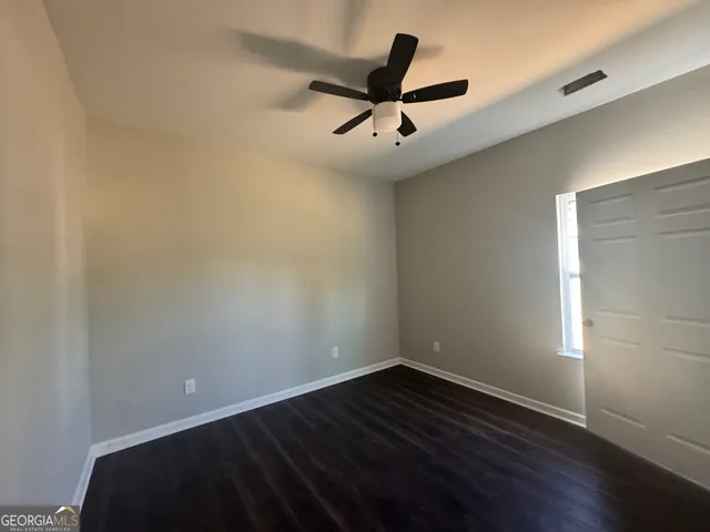 a view of empty room with wooden floor and ceiling fan